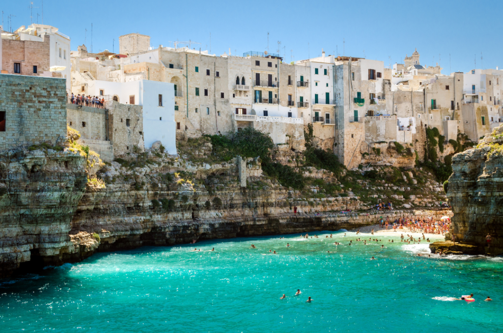 Cala di Polignano a Mare con case bianche sulla scogliera e mare turchese