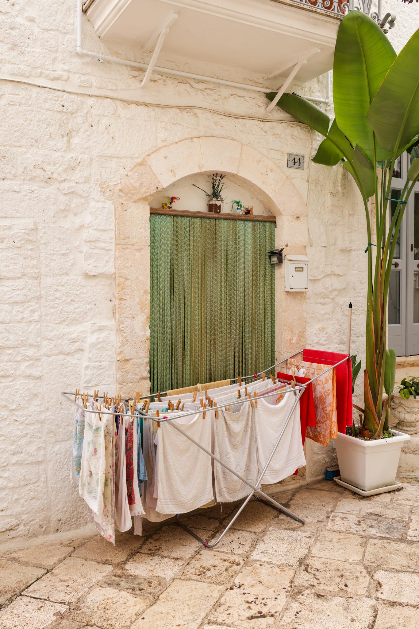 A quaint Italian street scene with laundry drying in front of a stone house, offering a glimpse into local life.