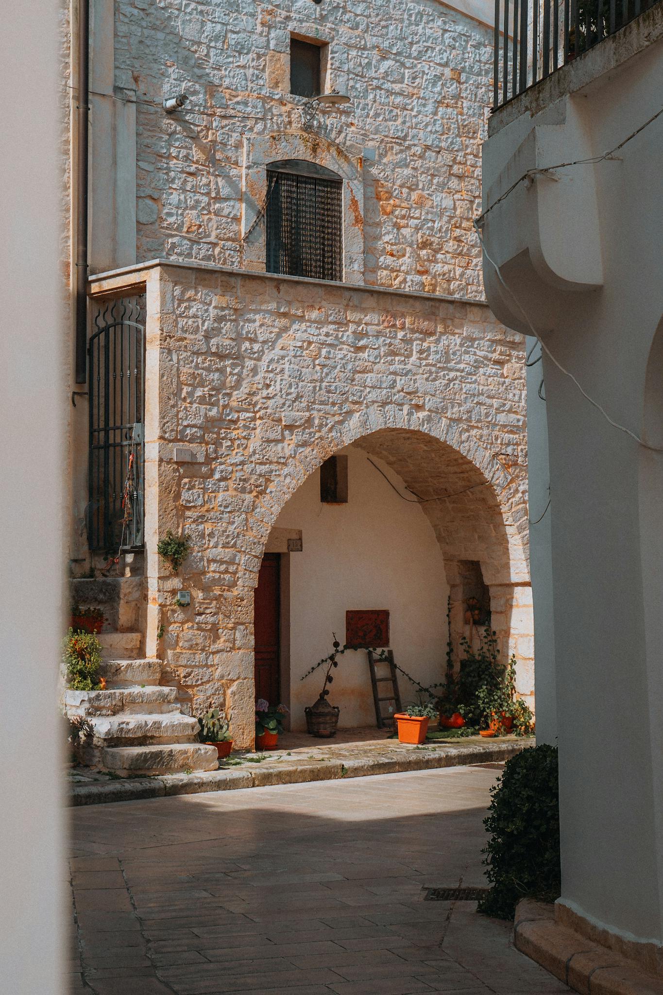 Charming stone archway and plants in a rustic alleyway of Sammichele di Bari, Italy
