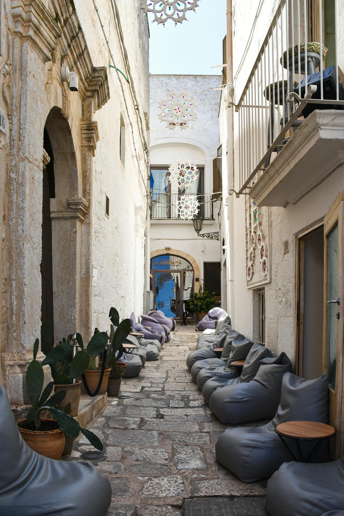 Scenic narrow alleyway in Apulia, Italy lined with cozy seating and vibrant decor.
