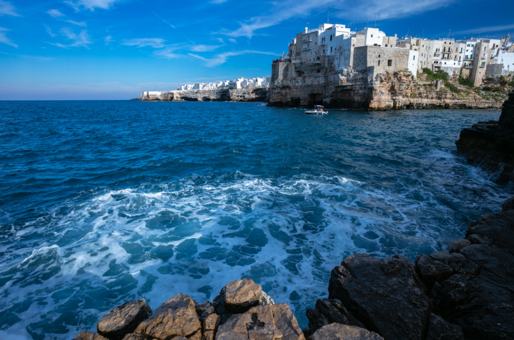 Polignano a Mare vista dal mare con borgo sulla scogliera e costa rocciosa