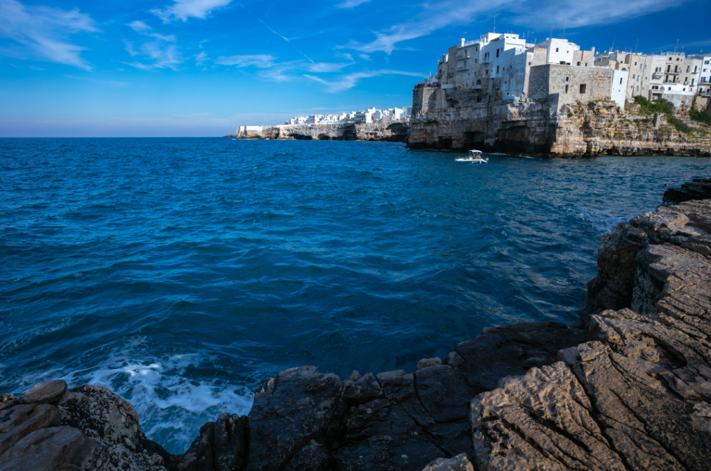 Polignano a Mare vista dal mare con scogliera rocciosa e borgo affacciato sull’Adriatico